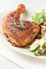 Spicy chicken leg with fresh salad on bright background. Close up.