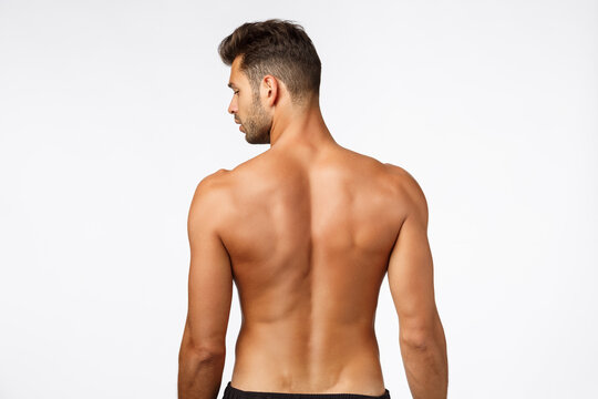 Rear view, attractive man from behind, athletic muscular back tanned sexy sportsman, turn face left, posing for gym advertisement, showing perfect body shape, fitness and exercises concept