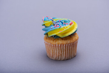 Close up of multicolored creamy cupcake with decorations with colorful stars, delicious and fabulous. Top view on gray background. Concept of birthday, celebration, sweet.