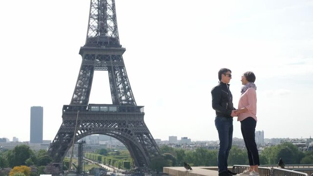 Affectionate couple kisses joining hands near Eiffel Tower