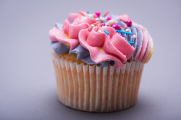 Close up of multicolored creamy cupcake with decorations with colorful stars, delicious and fabulous. Top view on gray background. Concept of birthday, celebration, sweet.