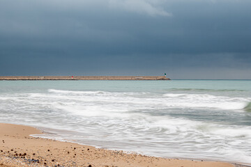  views of the breakwater of the port of Gandia, on a rainy and cloudy afternoon, with details of Posidonia balls, and sailboat jellyfish. 