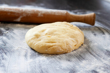 Fresh dough ready to bake. Bread dough on wooden kitchen counter with rolling pin