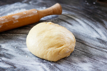 Fototapeta na wymiar Fresh dough ready to bake. Bread dough on wooden kitchen counter with rolling pin