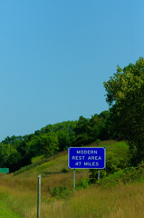 vertical image of a modern rest area sign off of the highway road trip