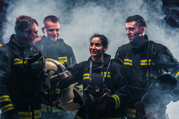 Team of firefighters standing the middle of the fire extinguisher's smoke inside the fire department