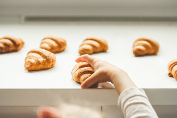 Fresh croissants on the white background. Little girls hand reaching out homemade pastry