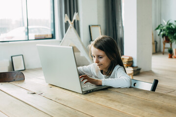 A girl learns at home at the computer