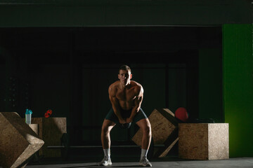 High contrast photo of a healthy fitness guy doing workout using a kettlebell