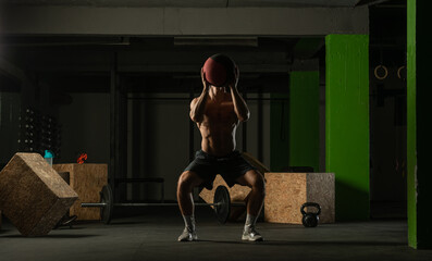 Obraz na płótnie Canvas Fit man throwing medicine ball doing ball slam against gym floor or shoulder press exercise..