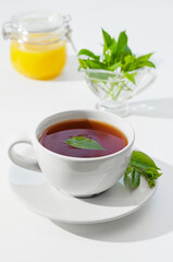 Cup of hot tea with lemongrass leaves and honey, on a white background. Shallow depth of field