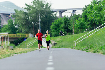 Young running couple jogging on an asphalt road in the park