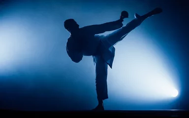 Foto op Aluminium Young man is practicing martial arts in sport gym © qunica.com