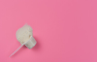 Collagen powder in a measuring spoon on a red solid background top view with copy space. Supplemental protein intake, natural supplement layout for skin and bone beauty and health.