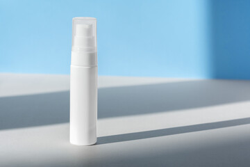 Cream dispenser template front view on blue surface with shadow from windows. Facial lotion, moisturizer, skin care beauty cosmetic bottle mockup. Brand spa product packaging mock up. Branding