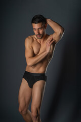 Fashion close-up portrait of a handsome male with bare torso posing in black underwear on isolated background