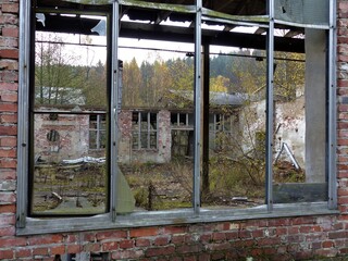 Blick durch ein kaputtes grosses Fenster in eine alte Fabrik ohne Dach - Lost Places