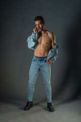 Handsome muscular shirtless young man standing confident, profile view, looking at camera