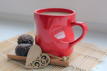 Coffee with milk and a smile in a cup. Heart made from coffee beans on a wooden table.