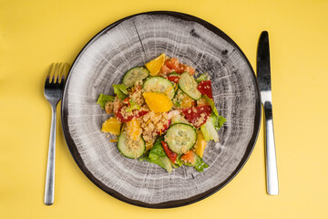 Fresh mix of salads with vegetables on a plate. Top view. Space for text. Yelow background
