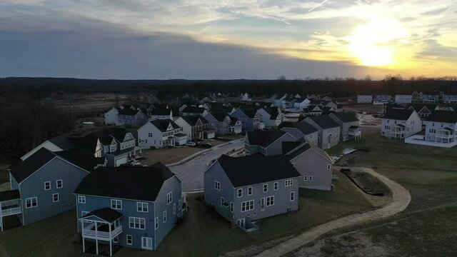 Flying above a typical American new construction neighborhood street in Maryland for the upper middle class, single family homes USA real estate with dramatic sky