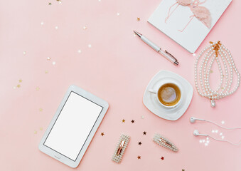 Home office workspace on pink background. Blogger concept with coffee and notebook. Flat lay with tablet and woman accessories.