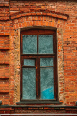 Fototapeta na wymiar An old window in a brick house. The building is made of red brick. Brown wooden frames. Historical building. Design and pattern template. Patterns made of old bricks.