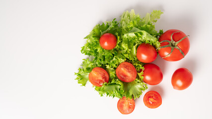 Juicy and ripe cherry tomatoes and green fresh lettuce on a white background. Top view. Copy space - obrazy, fototapety, plakaty