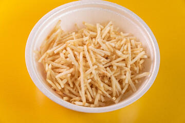 White bowl with potato straw on yellow background