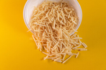 White bowl with potato straw on yellow background