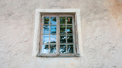 Old shabby  wooden window with painted frame and with reflection in glass. Close-up.