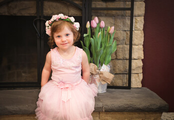 Close Up Portrait, 2 Years Old Toddler Girl with Big Blue Eyes, in light Pink Dress with Pink Flowers on her head, Sitting by the fireplace, Birthday Girl, Ukrainian Head bend, Little Princess 