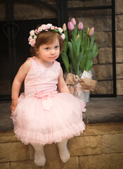 Close Up Portrait, 2 Years Old Toddler Girl with Big Blue Eyes, in light Pink Dress with Pink Flowers on her head, Sitting by the fireplace, Birthday Girl, Ukrainian Head bend, Little Princess 