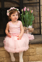 Close Up Portrait, 2 Years Old Toddler Girl with Big Blue Eyes, in light Pink Dress with Pink Flowers on her head, Sitting by the fireplace, Birthday Girl, Ukrainian Head bend, Little Princess 
