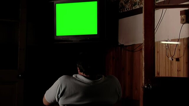Men Watching Television Set with Green Screen in a Dark Room. You can replace green screen with the footage or picture you want with “Keying” effect in AE (check tutorials in internet). 