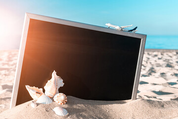 Summer background wood. Globe, seashell, airplane and starfish near black desk on sea beach in sunny day. Copy space for text.