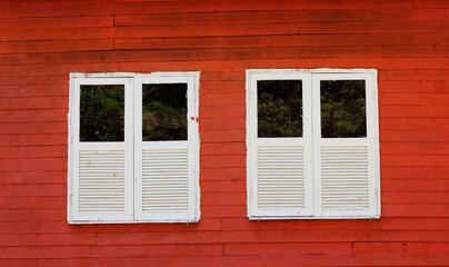 Retro wooden white window in red rustic house.