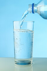 water is poured from a bottle into a glass close up. filling a glass with clean water from a bottle