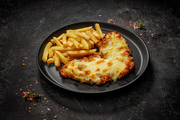 Fast food in a black plate. Golden brown chicken with cheese and french fries