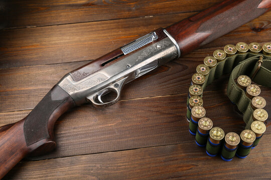 hunting rifle and cartridges on a wooden background, top view with copy space. 
