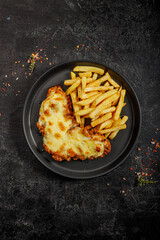 Fast food in a black plate. Golden brown chicken with cheese and french fries