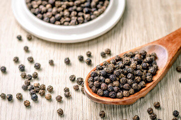 Fototapeta na wymiar Black pepper seed in a wooden spoon on the table, spice used in cooking
