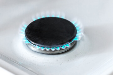 Gas burner with a blue flame on a gas stove, close-up