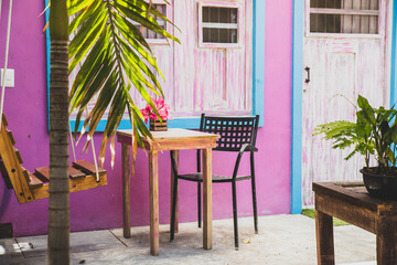 Pink and blue painted patio terrace in colourful Mexico with wooden table, seats and a swing chair