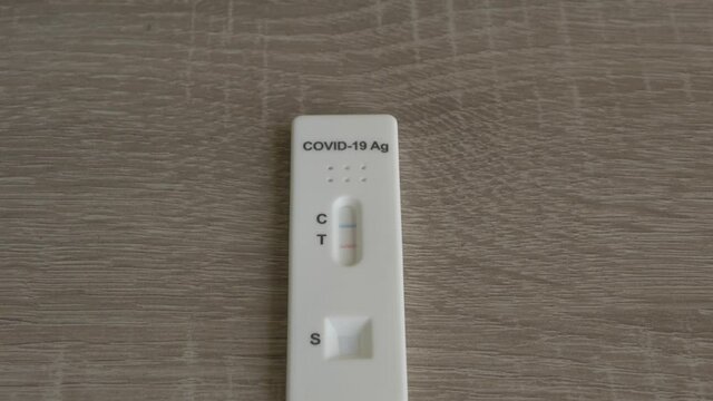 Tilting down fast to slow to a covid 19 positive antigen test on a wooden table, 23.98 fps