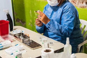 Coronavirus vaccine concept. Work team in light blue safety uniform, mask and glasses prepare the vial and syringe of the coronavirus vaccine. COVID-19 virus solution, cure for global pandemic.