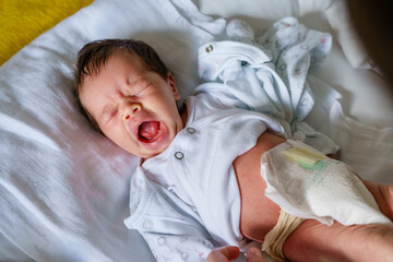 Top view on caucasian baby sleepy yawing while changing diapers and clothes lying on the bed at...