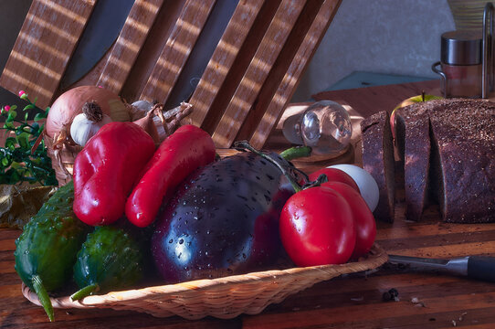 Fresh vegetables on a wooden table with black rustic bread. The bread is cut with a knife. Light streaks through the blinds.