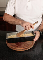 Close-up detail shot of Caucasian man's hands placing, in a baking dish, the preparation to cook an apple pie.