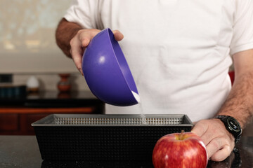 Close-up detail shot of Caucasian man's hands spreading sugar or flour in a bowl.